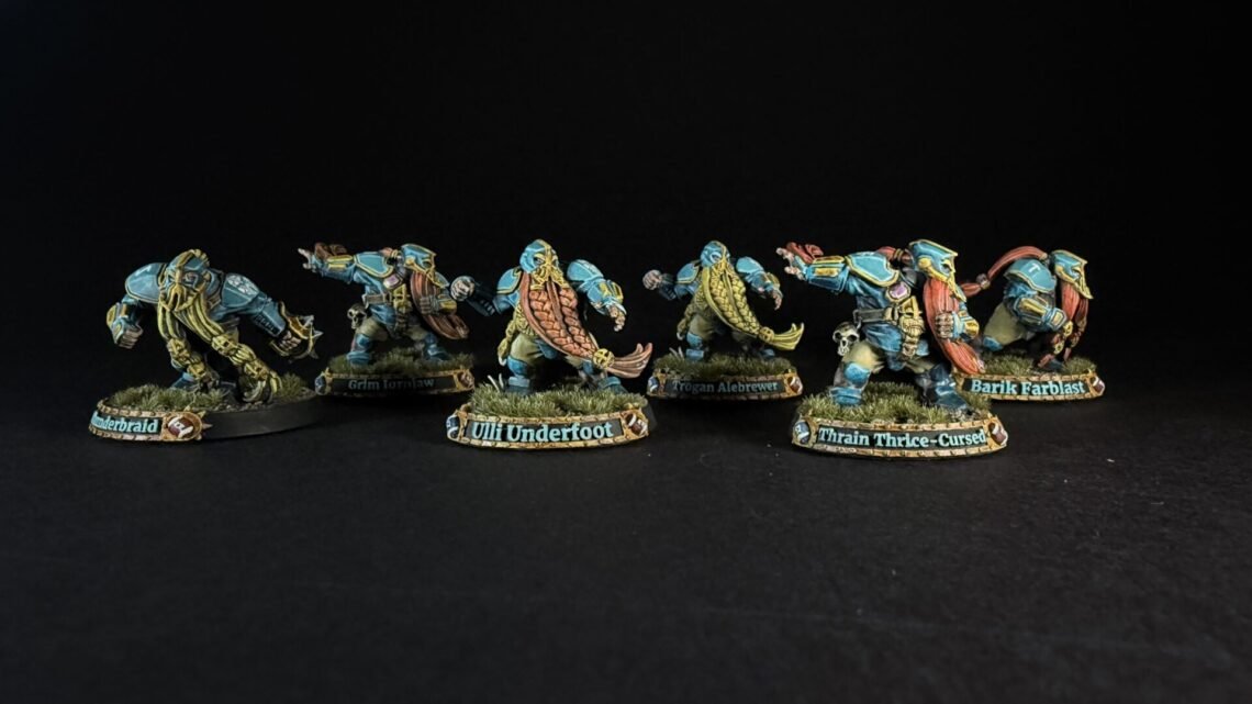 Six teal-armored dwarf miniatures with long braided beards on grassy round bases, labeled with names like Uli Underfoot and Train Thrice-Cursed.
