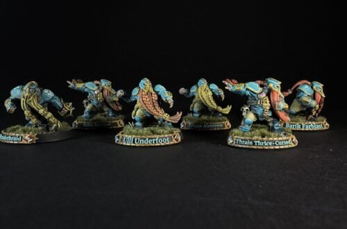 Six teal-armored dwarf miniatures with long braided beards on grassy round bases, labeled with names like Uli Underfoot and Train Thrice-Cursed.