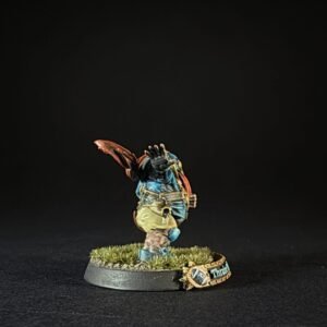 Painted tabletop miniature of a fantasy character in blue clothing on a grassy round base, mid-action pose.