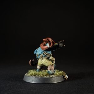 Painted tabletop miniature of a bearded adventurer wearing a blue backpack and red scarf, standing on a grassy base with one arm raised.