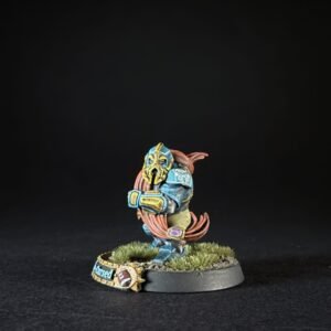 Hand-painted tabletop miniature: blue armored warrior with yellow trim, orange hair, standing on a grassy base with a small decorative banner nearby.