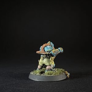 Small hand-painted tabletop miniature of a blue-armored dwarf with a braided beard, standing on a grassy base with tufts of grass.