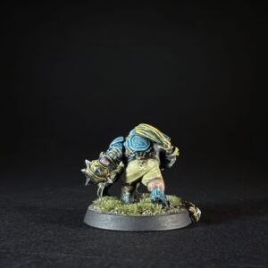 Fantasy painted miniature: blue-and-gold armored warrior hunched over a spiked weapon on a grassy base against a black background.