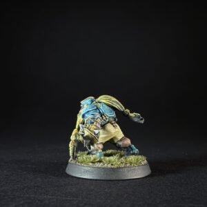 Small painted fantasy miniature: a blue-armored humanoid with long yellow hair, crouching on a grassy round base against a black background.