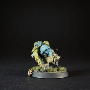 Painted fantasy miniature crouching on a grassy base, wearing blue armor with yellow trim and a large hooked weapon at his side.