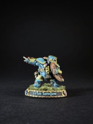 Painted dwarf warrior miniature in blue armor, pointing forward with a shield, on a grassy base labeled Grim Ironjaw.