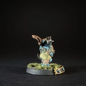 Painted miniature of a turtle-like fantasy creature on a grassy round base, standing with one hand raised, wearing blue armor and a backpack.