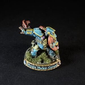 Painted dwarf warrior miniature in blue armor with an orange cape, raising a shield on a grassy rocky base labeled Thrain Thrice-Cursed.