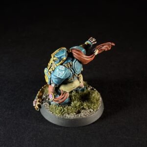 Back view of a painted fantasy miniature in teal armor with a red scarf, charging forward on a grassy base.