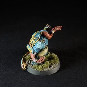 Painted tabletop miniature of a blue-armored warrior with red scarf standing on a grassy base