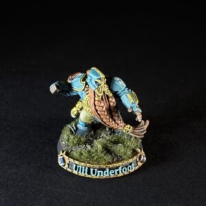 Painted fantasy miniature of a blue-armored warrior with a brown shield, standing on a grassy base; edge text reads 'Ulli Underfoot'.