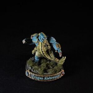 Fantasy miniature of a blue-and-gold armored fighter with a long golden cloak, standing on a grassy base; base reads 'Trogan Alebrewer'