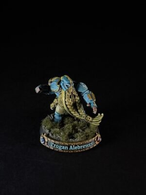 Fantasy miniature of a blue-and-gold armored fighter with a long golden cloak, standing on a grassy base; base reads 'Trogan Alebrewer'