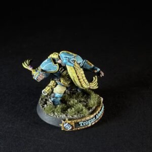 Painted blue-and-gold armored fantasy miniature charging forward on a grassy round base with a decorative rim edge.