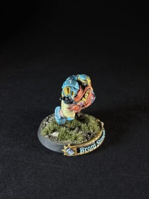 Painted fantasy miniature: blue-armored figure with orange hair on a rocky, grassy base and a decorative banner along the base.