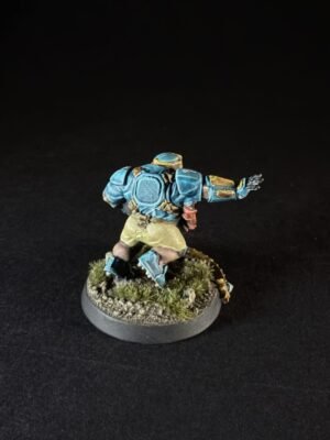 Back view of a blue armored miniature figure running on a grassy, rocky base