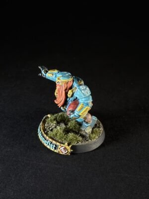 Miniature dwarf warrior in blue armor with an orange beard, raised arm, on a grassy base.