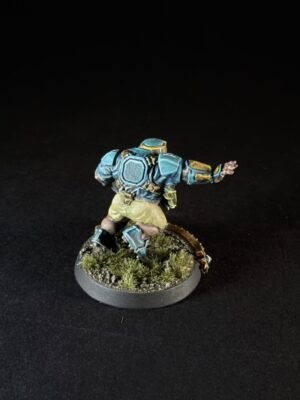 Miniature sci‑fi soldier in blue armor running on a grassy base.
