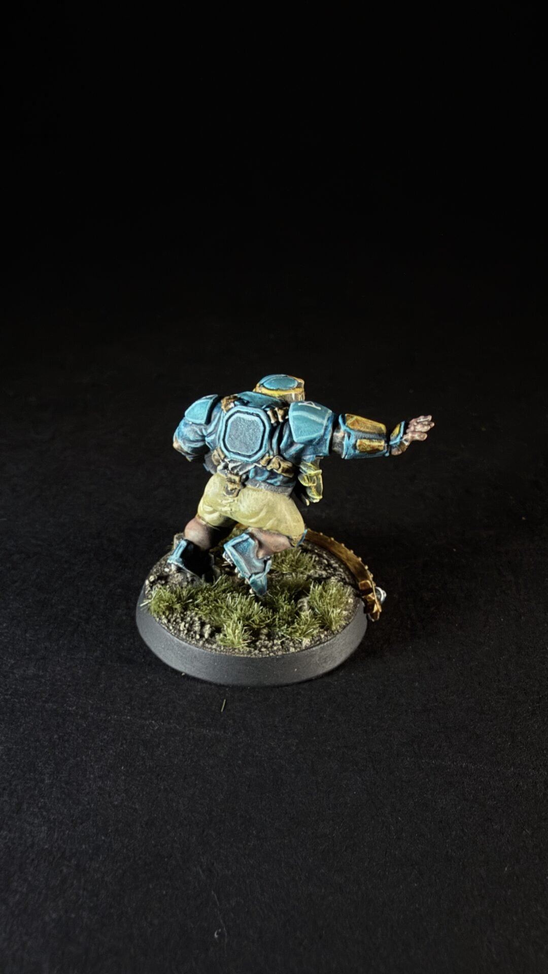 Miniature sci‑fi soldier in blue armor running on a grassy base.