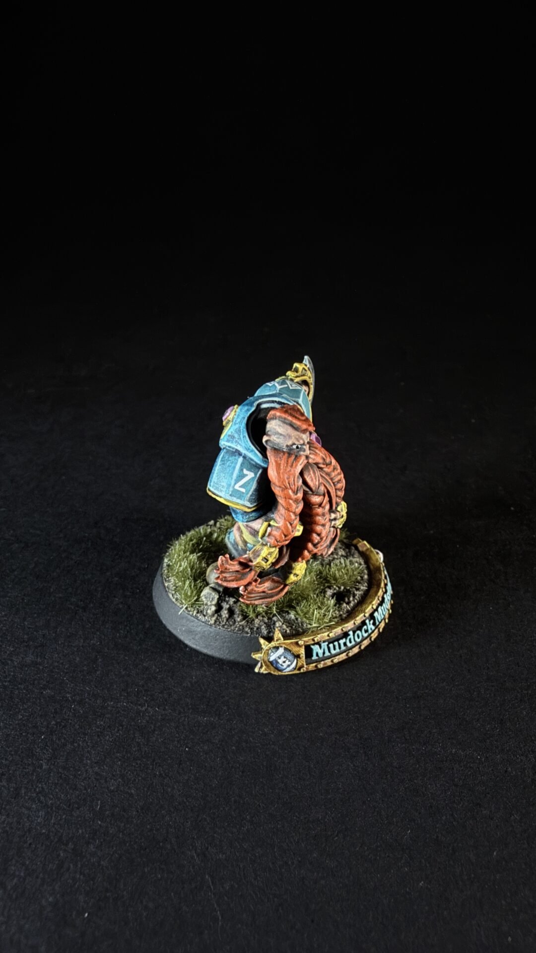 Small painted sci-fi mini figure with orange tentacles and blue armor, standing on a grassy base with a 'Murdock' name banner.