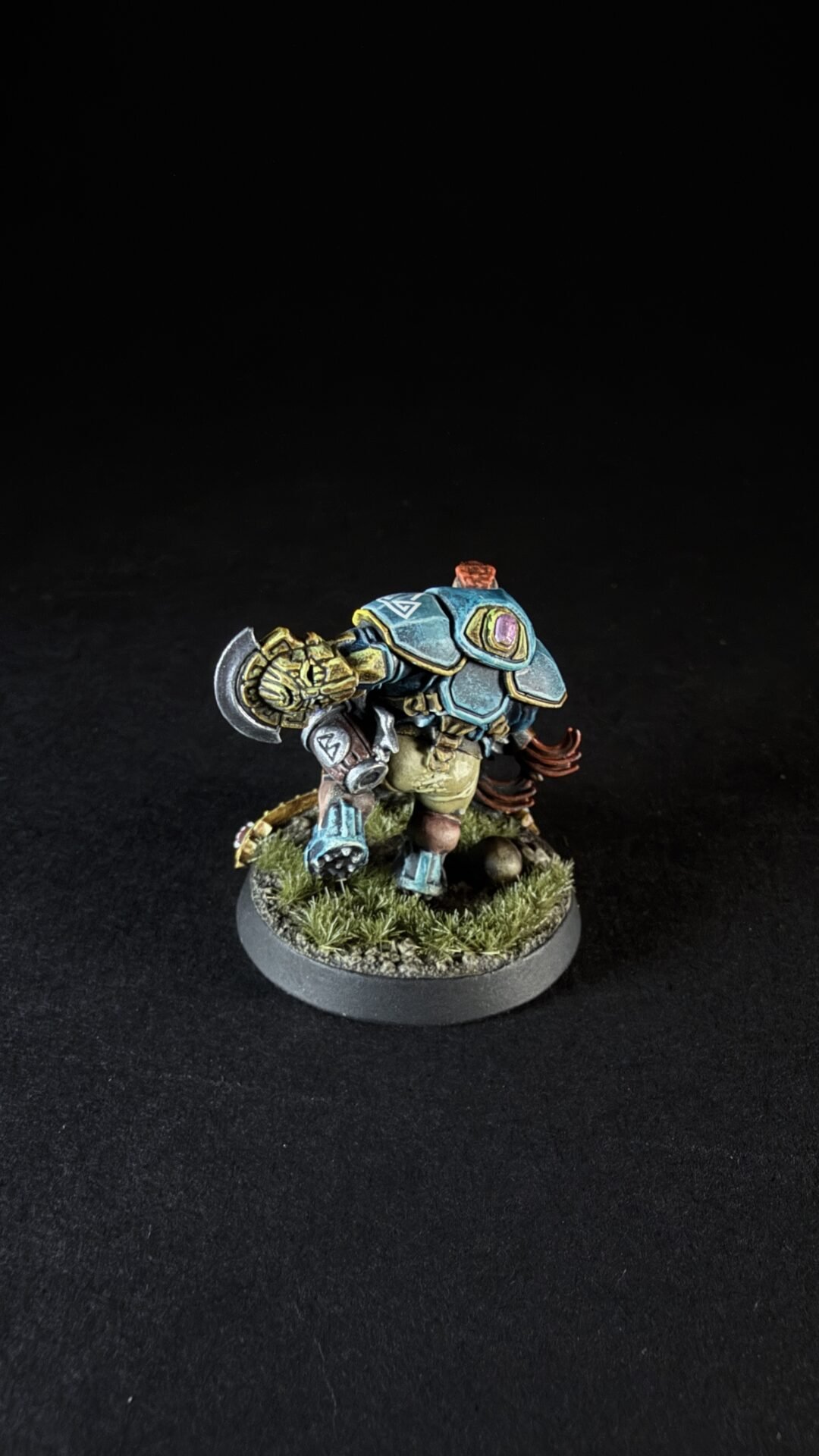 Miniature orc warrior in blue armor, wielding a hammer, on a grassy base of terrain.