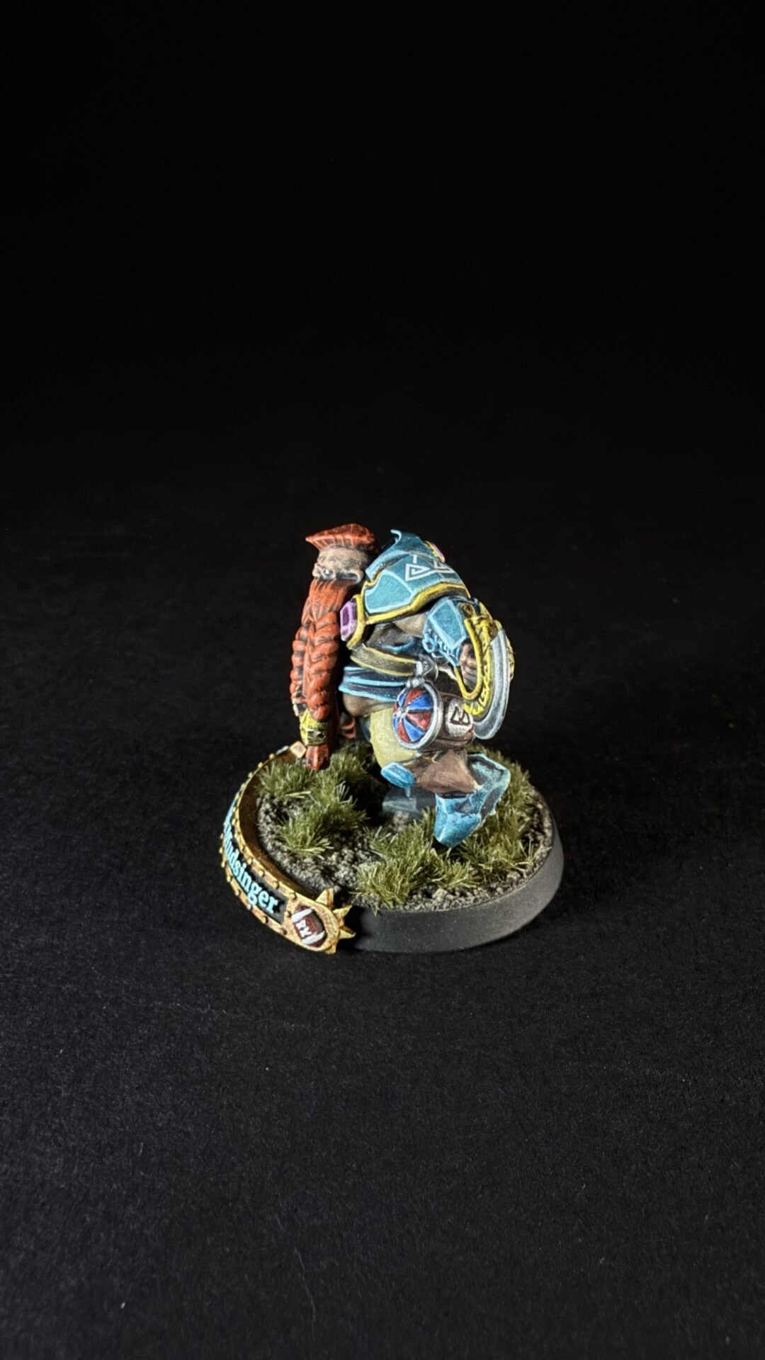 Colorfully painted fantasy miniature: a blue-armored warrior with a red left arm, standing on a grassy, textured base.