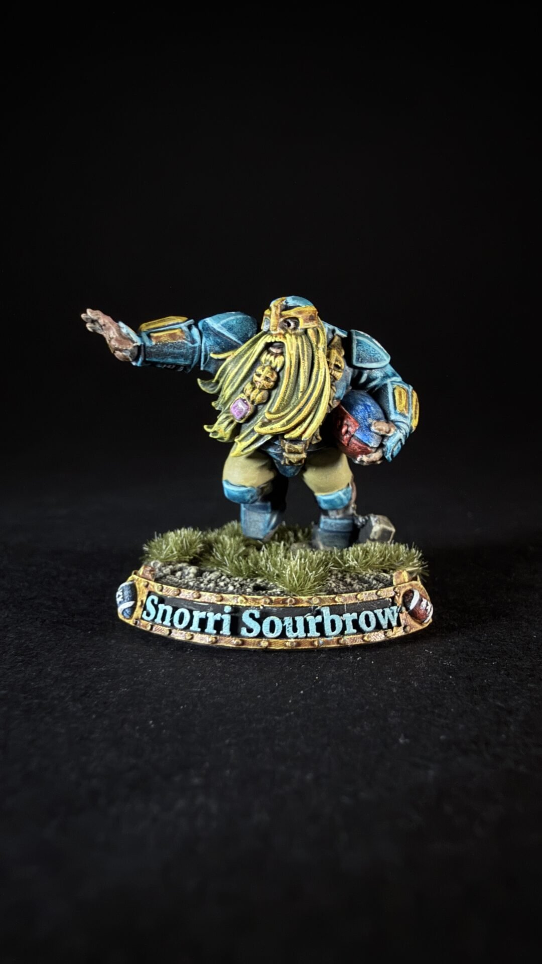 Blue-armored dwarf miniature with a long yellow beard, posed with one arm outstretched, standing on a grassy base labeled 'Snorri Sourbrow'.
