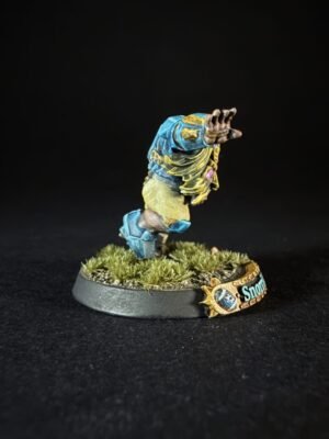 Painted tabletop mini figure of a blue-and-yellow armored character raising its arm, mounted on a grassy base with a banner reading 'Snow' nearby.