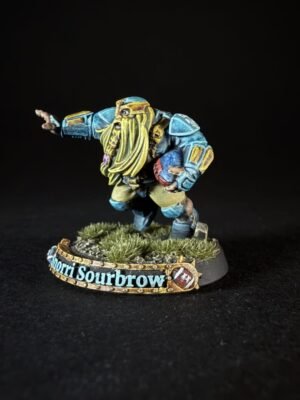 Colorful dwarf miniature in blue armor with a long yellow beard, standing on a grassy base with a decorative banner reading 'Shorri Sourbrow'.