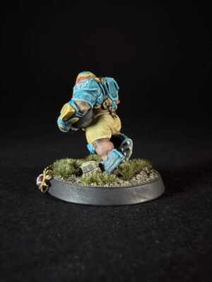 A painted fantasy miniature of a bearded warrior in blue armor sprinting across a grassy base on a round stand