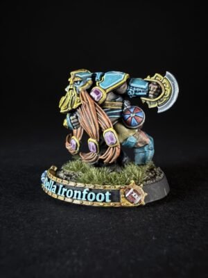 Della Ironfoot miniature: a colorful dwarf warrior in blue and gold armor, wielding a large ornate battle axe, standing on a grassy base with a banner bearing the name 'Della Ironfoot'.