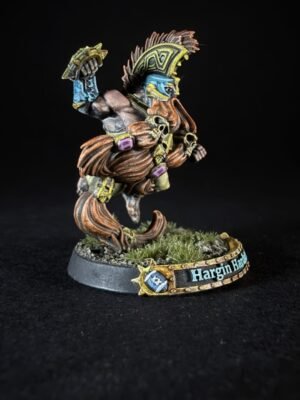 Fantasy miniature of a muscular warrior with blue face paint, ornate yellow helmet, fur cloak, and skull pendants, standing on a grassy base labeled 'Hargin'.