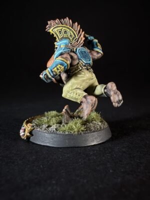 A fantasy miniature of a muscular orc in blue and gold armor running on a rocky, grassy base with a decorative yellow crest on its back.