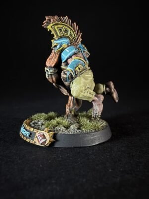 Painted fantasy miniature of a warrior running, wearing a blue and yellow winged helm with brown hair and armor, on a grassy textured base.