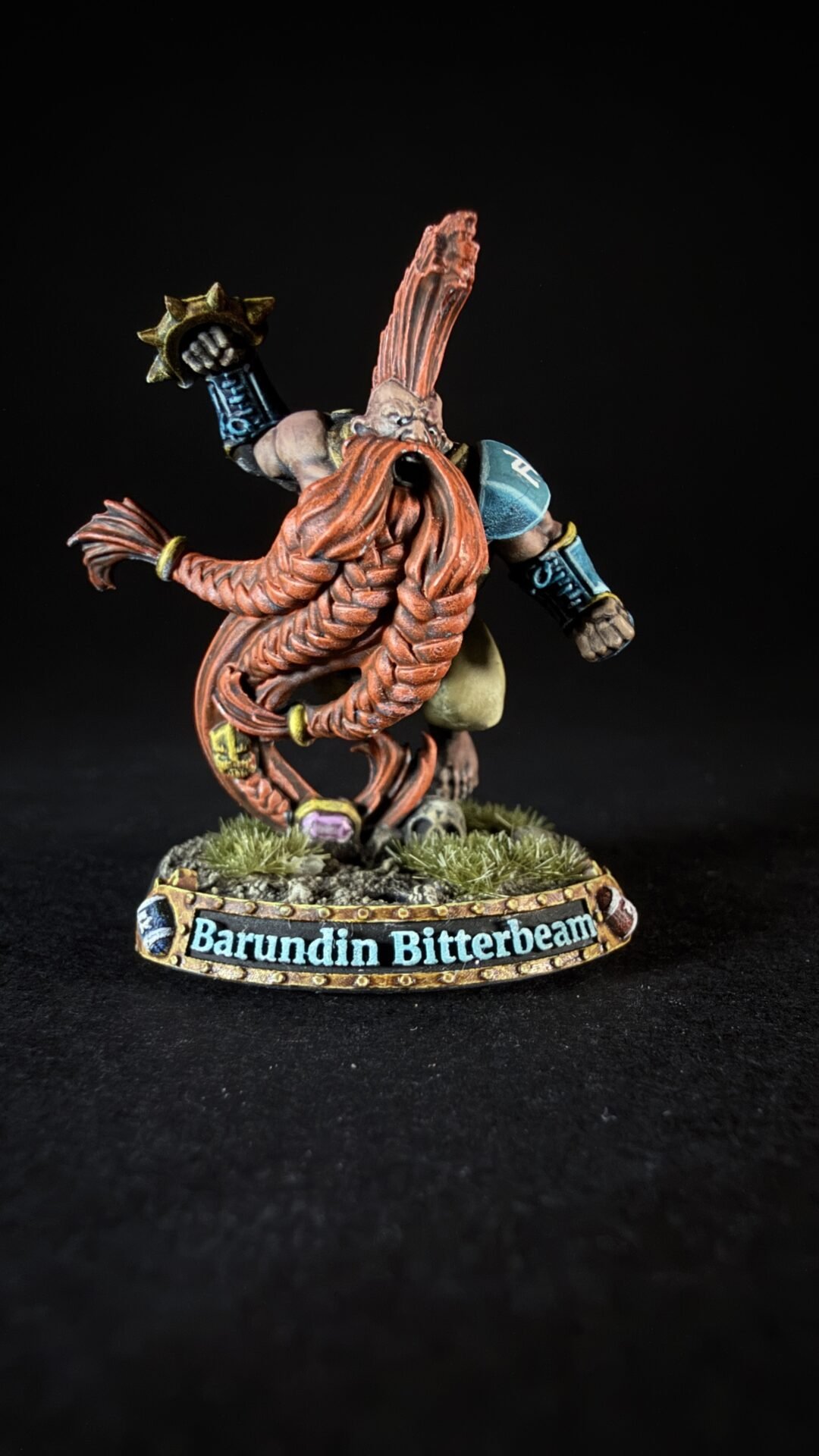 Miniature dwarf warrior Barundin Bitterbeam, with a long braided red beard, raised hammer, standing on a grassy base.