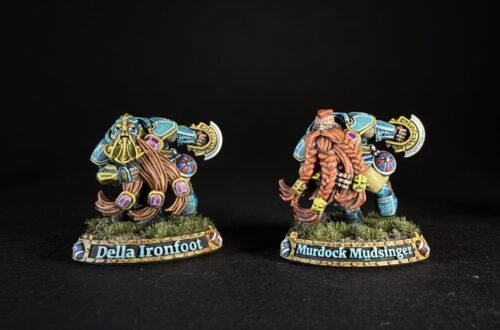 Two colorful fantasy dwarf miniatures on grassy bases, facing opposite directions, with name banners reading 'Della Ironfoot' and 'Murdock Mud­singer' (or similar).