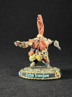 Miniature fantasy orc warrior Grim Ironjaw with tall orange hair plume, outstretched arms, detailed armor, standing on rocky base labeled Grimg Ironjaw (sic).