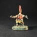 Miniature fantasy orc warrior Grim Ironjaw with tall orange hair plume, outstretched arms, detailed armor, standing on rocky base labeled Grimg Ironjaw (sic).