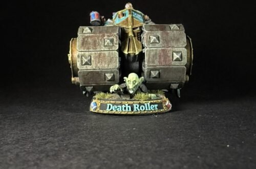 Miniature model of a Death Roller war machine with a goblin crew, on a grassy base labeled 'Death Roller' against a black background.