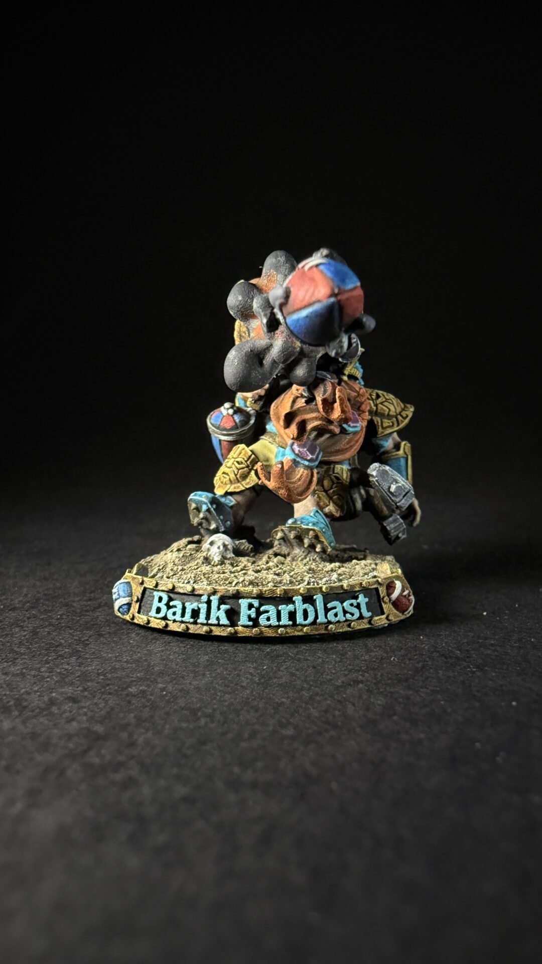 Painted fantasy miniature of Barik Farblast in colorful armor, posed on a rocky base.