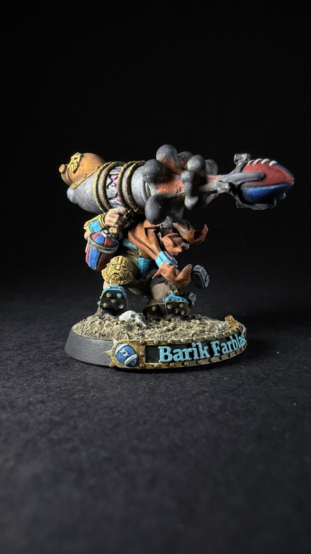 Colorful painted fantasy dwarf figure firing a large rocket launcher, standing on a rocky diorama base.