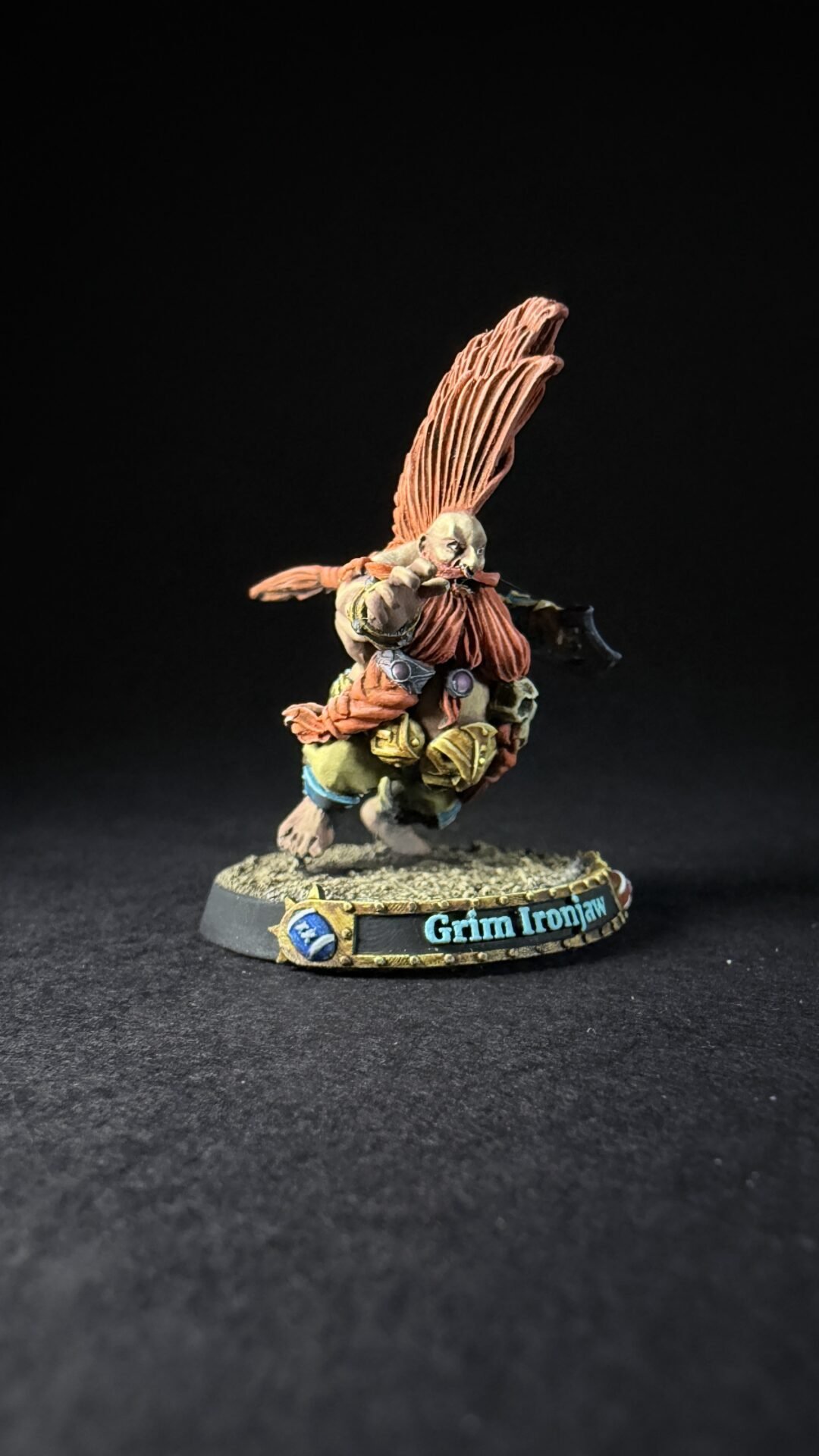 Miniature figure with large orange wings, wearing armor and furring, standing on a textured base labeled 'Grim Ironjaw'