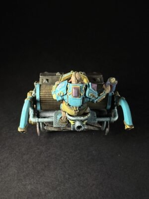 Rear view of a painted miniature sci‑fi combat crawler with teal armor and gold highlights, set against a black backdrop.