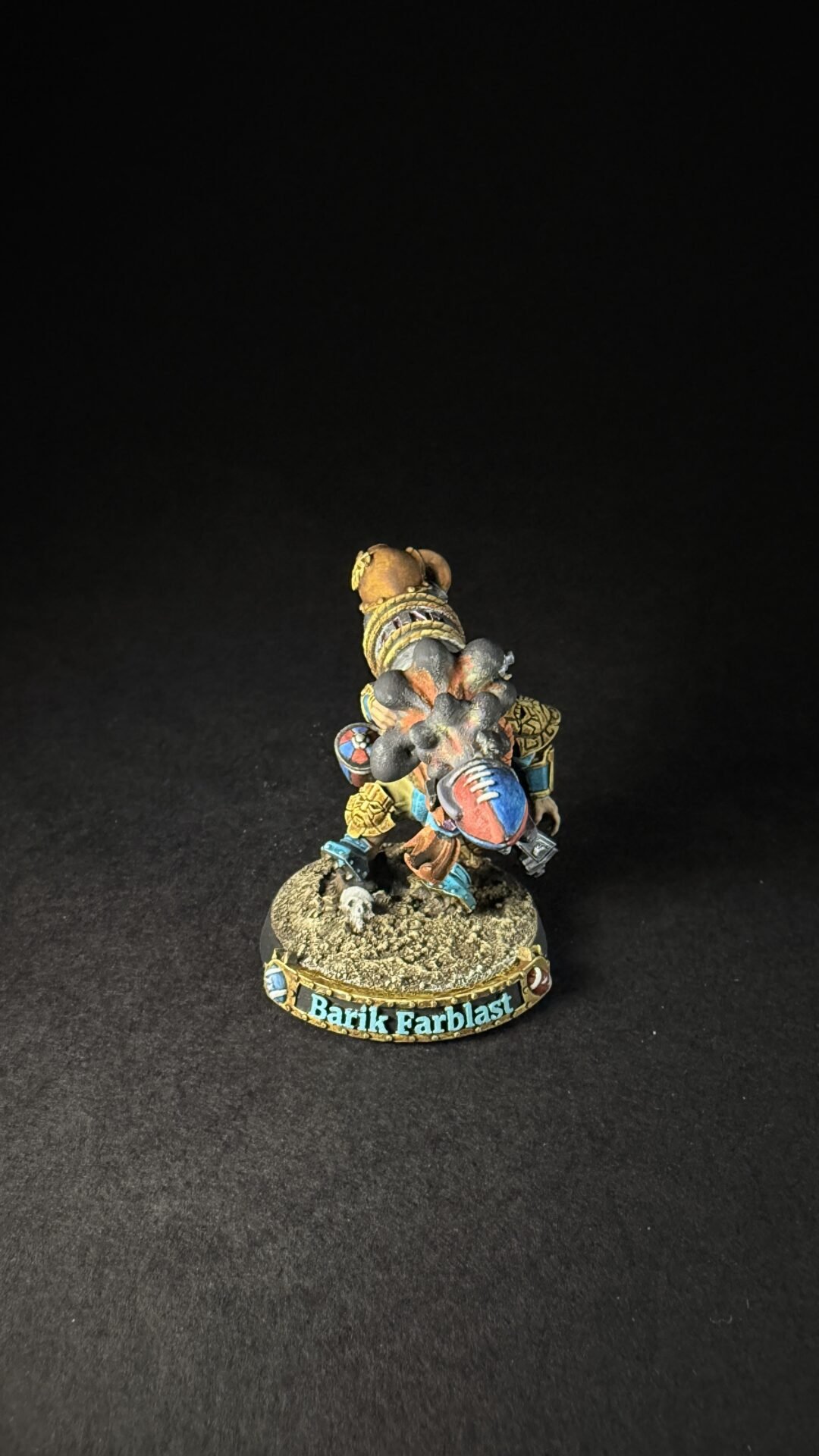 Colorful painted dwarf miniature in ornate armor, standing on a rocky base labeled Barik Farblast, facing right.