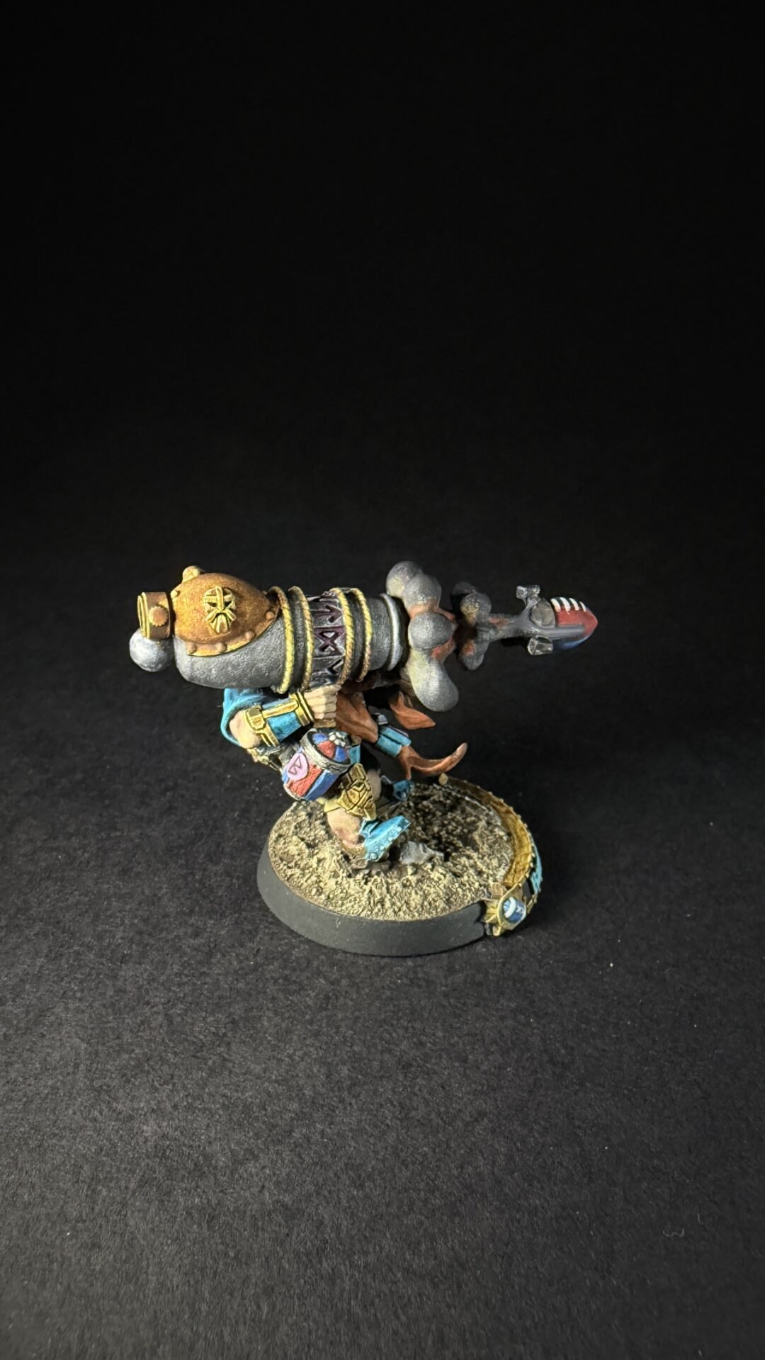 A painted fantasy dwarf warrior in blue and gold armor wielding a giant ornate hammer, standing on a textured base.
