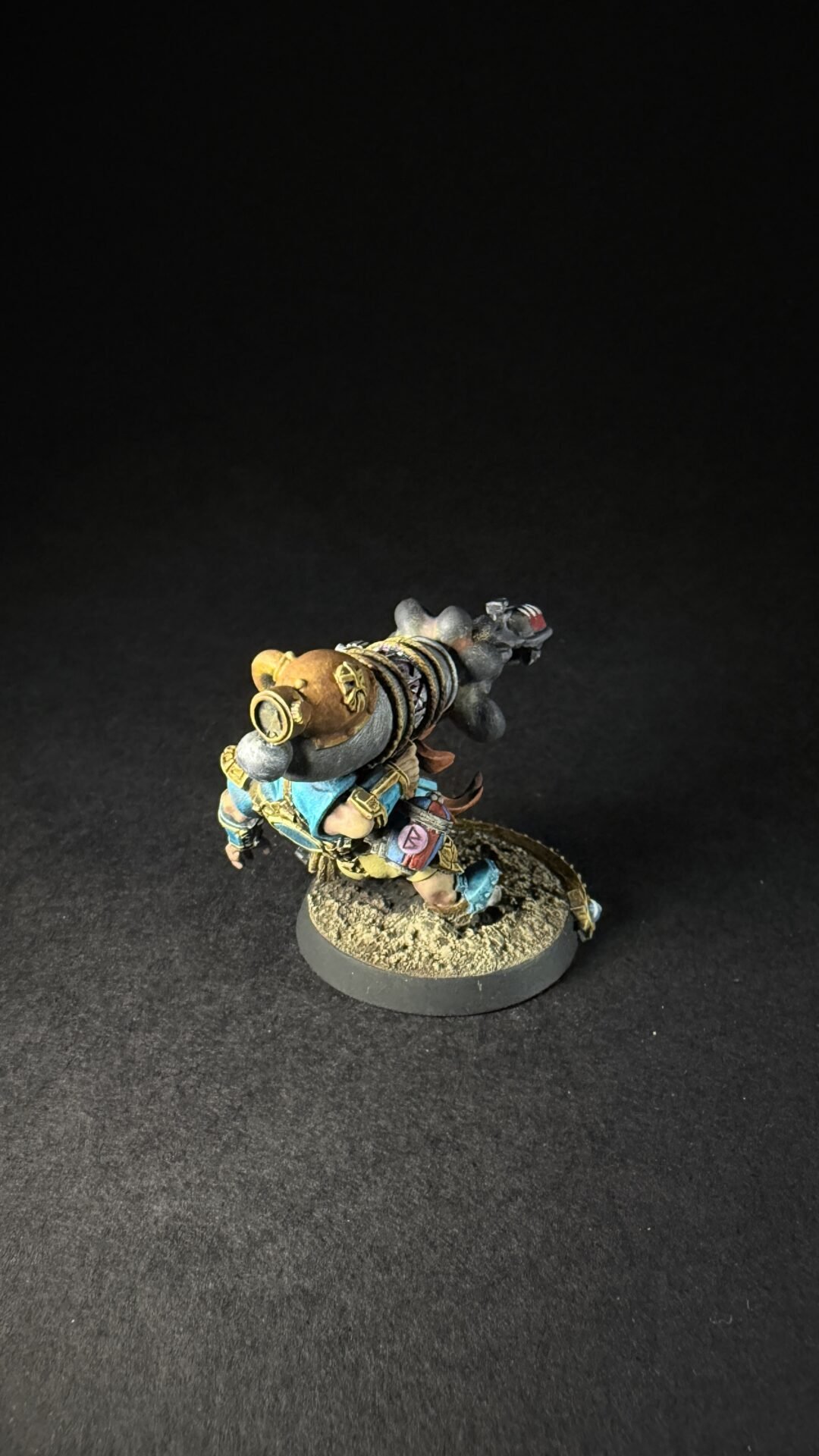 Painted fantasy dwarf miniature with a large backpack and gear on a rocky base.