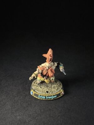 Small fantasy miniature Grim Ironjaw standing on a rocky base, painted armor with orange plumes and a weapon in hand.