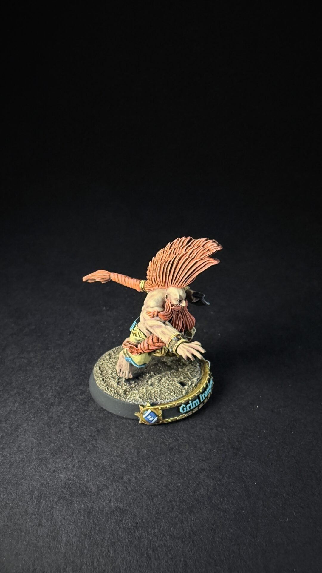Miniature fantasy warrior figurine with long orange hair in a dynamic pose on a rocky display base.