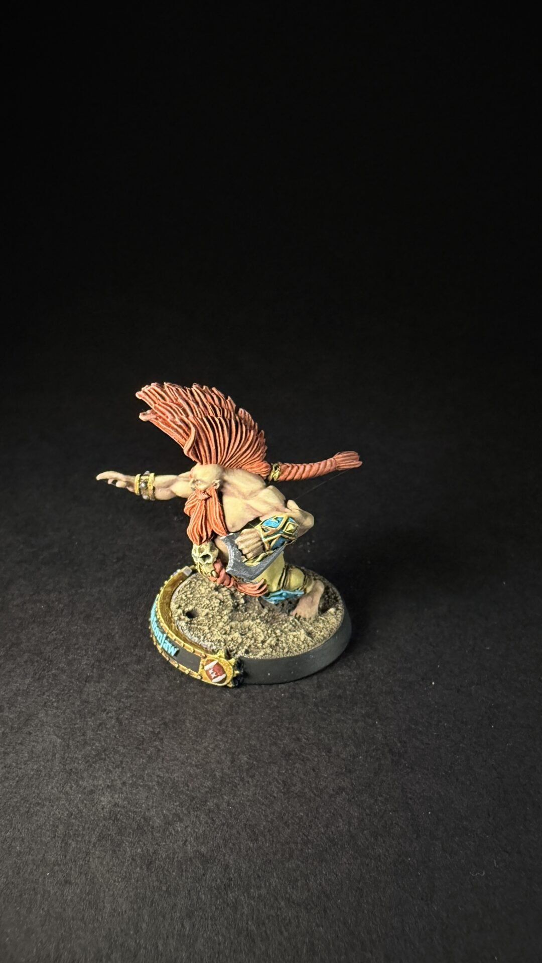 Painted fantasy miniature of a winged warrior with red hair leaping forward on a textured base.