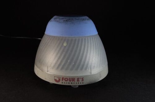Cone-shaped, ribbed lamp with a blue top and gray base on a dark surface; brand reads 'FOUR'S SCIENTIFIC'.